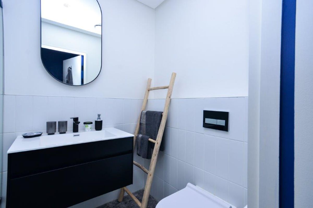 Modern bathroom featuring a sleek wall-mounted vanity with integrated basin, wall-mounted toilet with flush plate, and clean white tiled splashback.