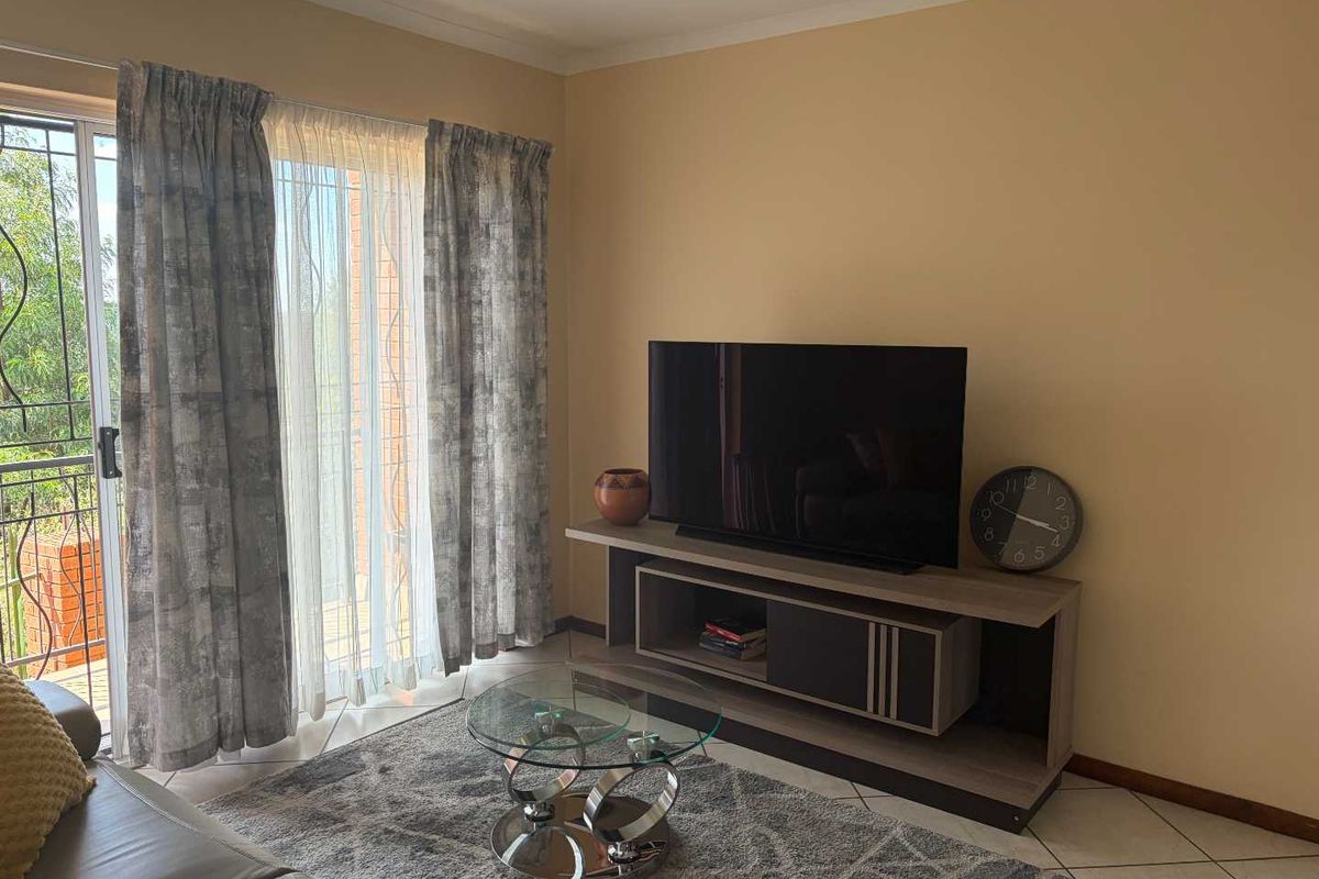 A living room featuring tiled flooring and a sliding glass door providing access to an outdoor balcony area.
