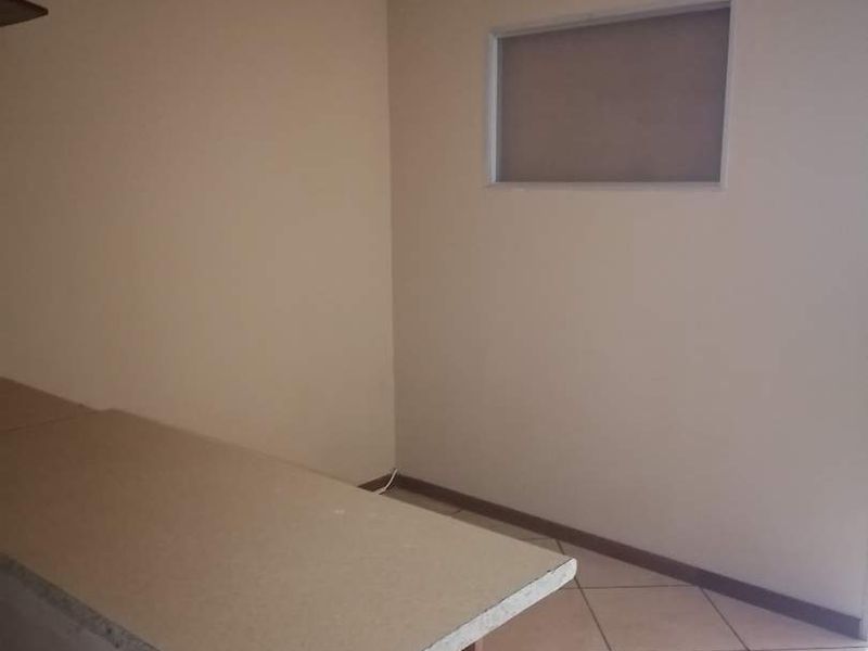 An empty kitchen area featuring tiled flooring, a breakfast bar with an unfinished edge, and an internal window.