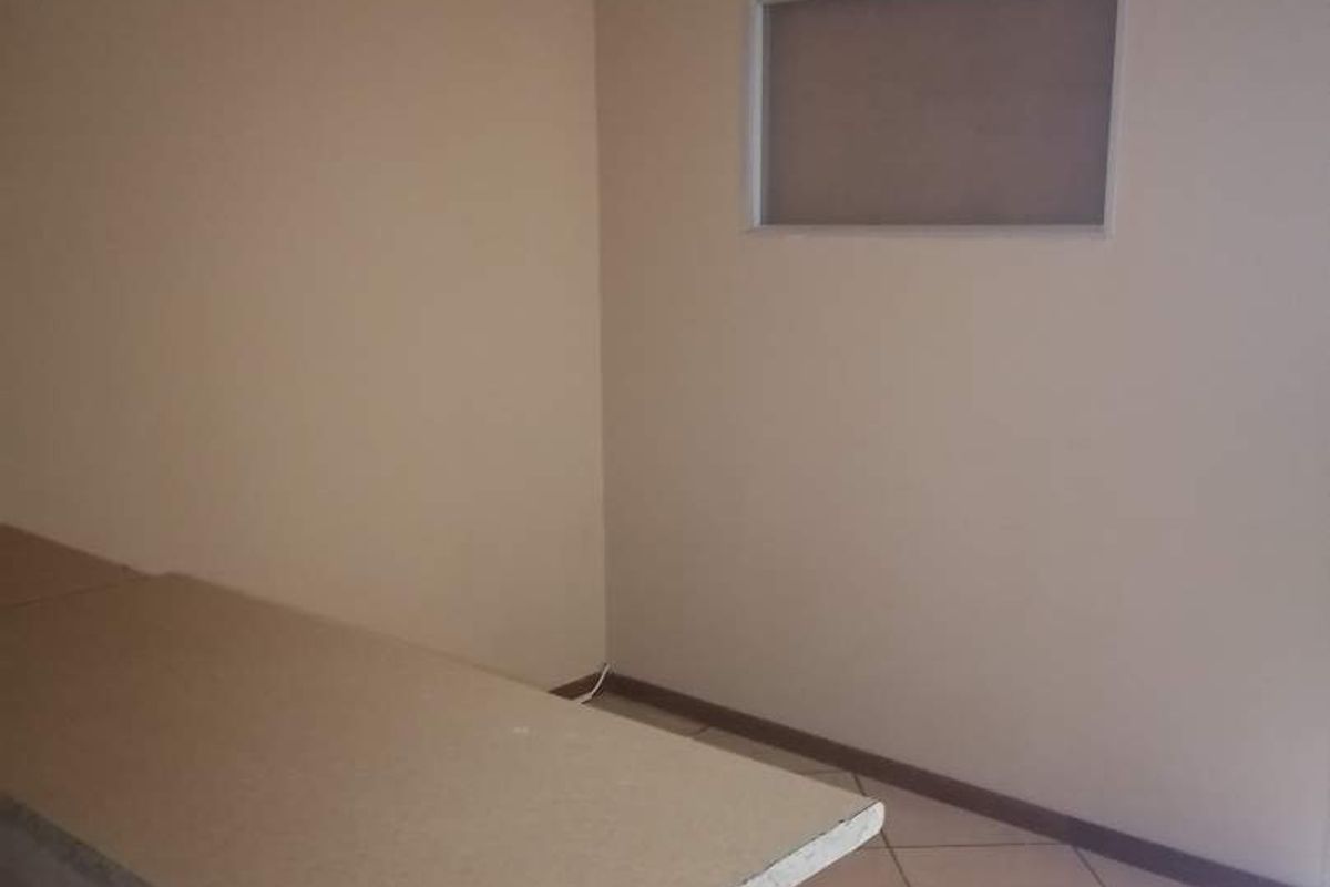 An empty kitchen area featuring tiled flooring, a breakfast bar with an unfinished edge, and an internal window.