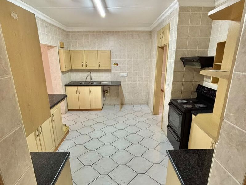 A functional kitchen featuring tiled flooring, built-in cabinetry, and a freestanding stove, offering a blank canvas for potential modern updates and renovation.