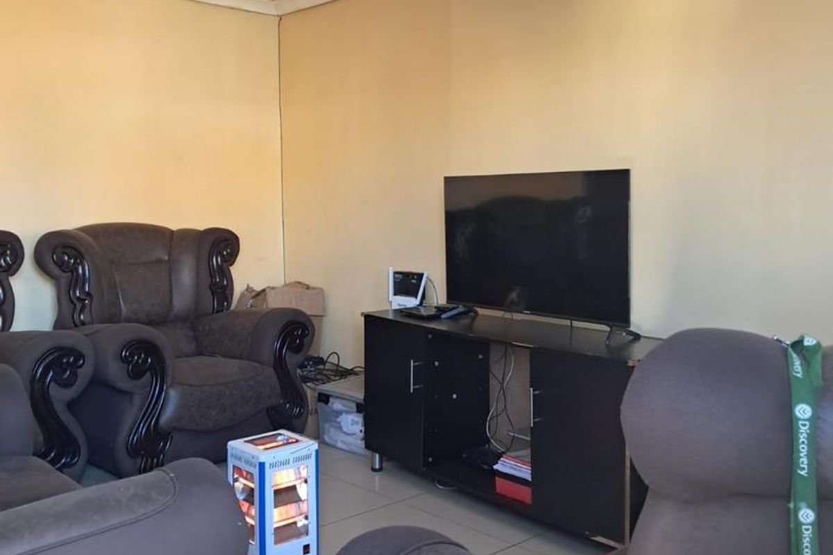 A living room featuring tiled flooring and visible ceiling water damage, offering a functional space that could benefit from cosmetic updates and repairs.