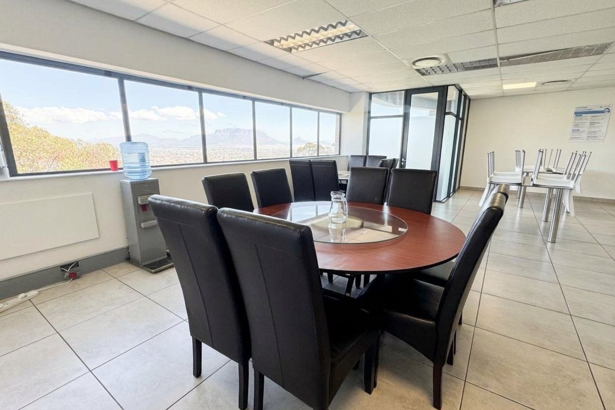 A bright office space featuring tiled flooring, a suspended ceiling with recessed lighting, and large windows offering expansive views.