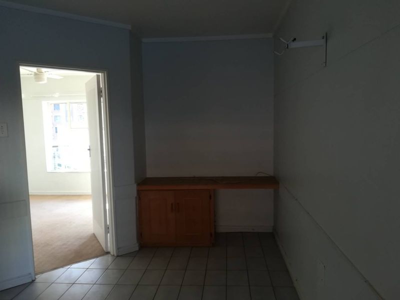 A functional utility space featuring tiled flooring and built-in cabinetry, offering versatile storage or workspace potential within the apartment.