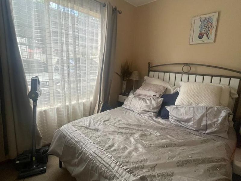 A standard bedroom featuring carpeted flooring and a large window that allows for natural light.