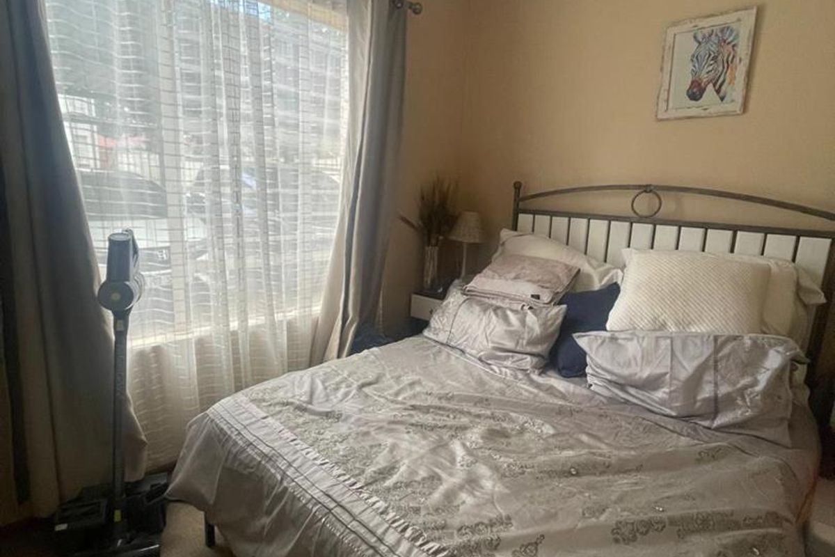 A standard bedroom featuring carpeted flooring and a large window that allows for natural light.