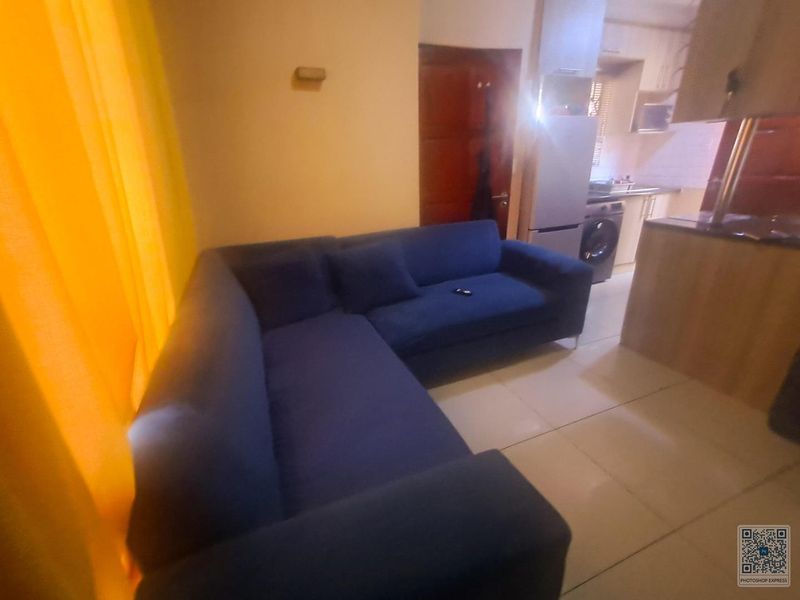 Open plan living area featuring tiled flooring and a compact kitchen with built-in cabinetry and appliances.