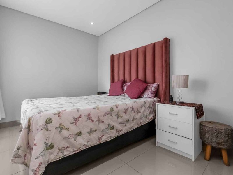 A well-maintained bedroom featuring neutral wall tones, tiled flooring, and recessed ceiling lighting, creating a clean and comfortable living space.