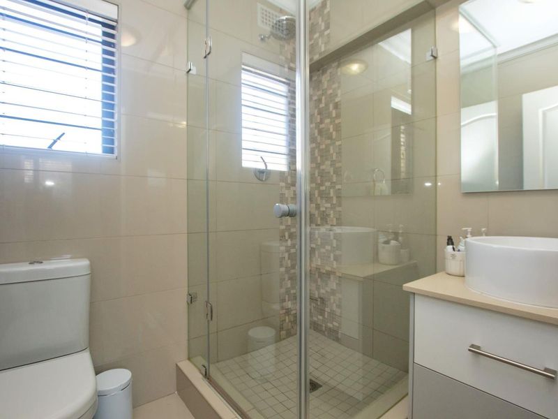 Modern bathroom featuring a glass-enclosed shower with mosaic tile accents, a contemporary vessel sink vanity, and neutral wall tiling.