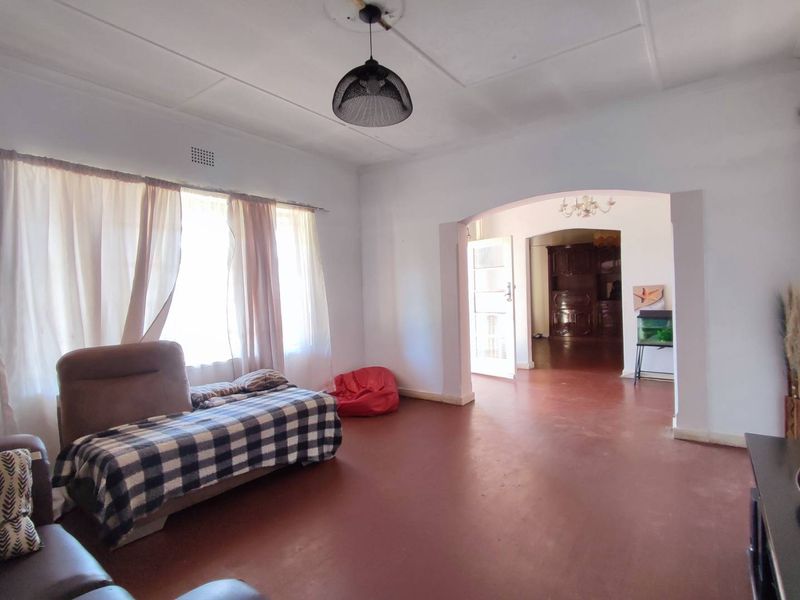 Spacious living area featuring an arched entryway, high ceilings with a decorative rose, and large windows allowing for natural light.