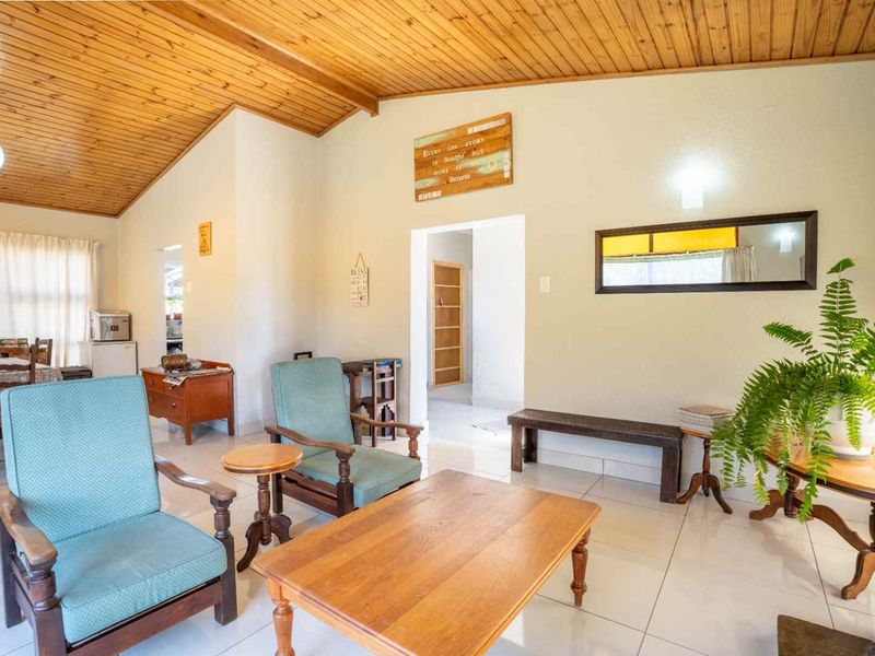 A spacious living area featuring a high timber-clad vaulted ceiling and neutral tiled flooring, providing a bright and open atmosphere.