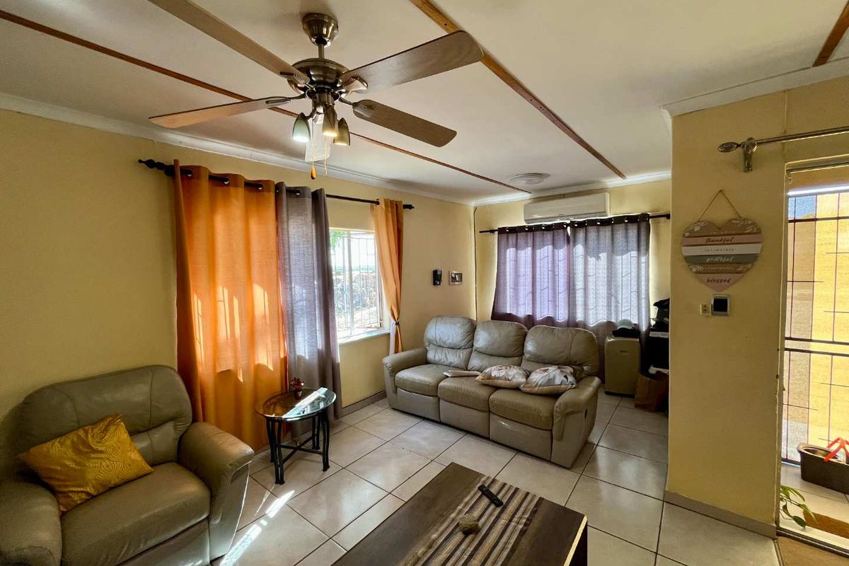 A living room featuring tiled flooring, a ceiling fan, and a wall-mounted air conditioning unit.