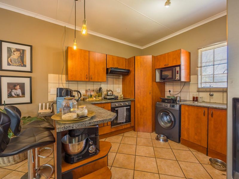 Functional kitchen featuring wood-finish cabinetry, granite countertops, built-in oven, extractor fan, and integrated microwave with tiled flooring and backsplash.