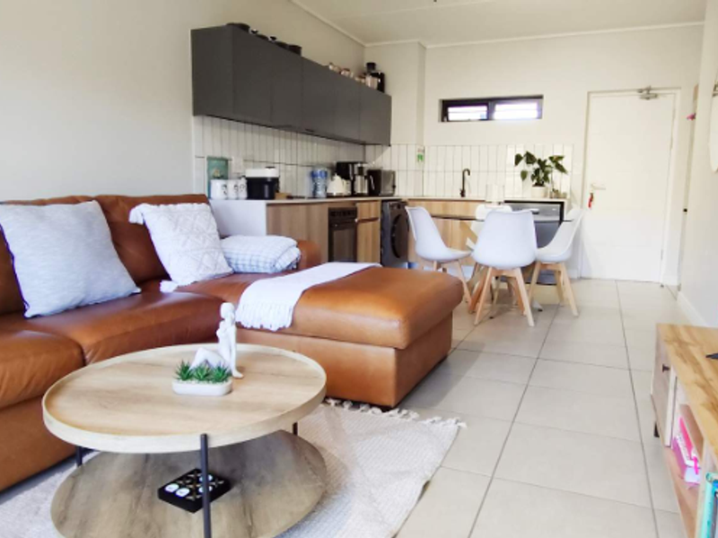 An open-plan living and kitchen area featuring modern cabinetry, tiled flooring, and a functional layout suitable for contemporary apartment living.