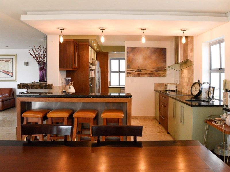 Open plan kitchen featuring granite countertops, built-in cabinetry, and a breakfast bar, seamlessly integrated with the living and dining areas.