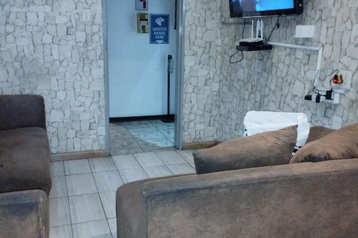 A living room area featuring stone-cladding wall finishes and tiled flooring, currently set up with a wall-mounted television.