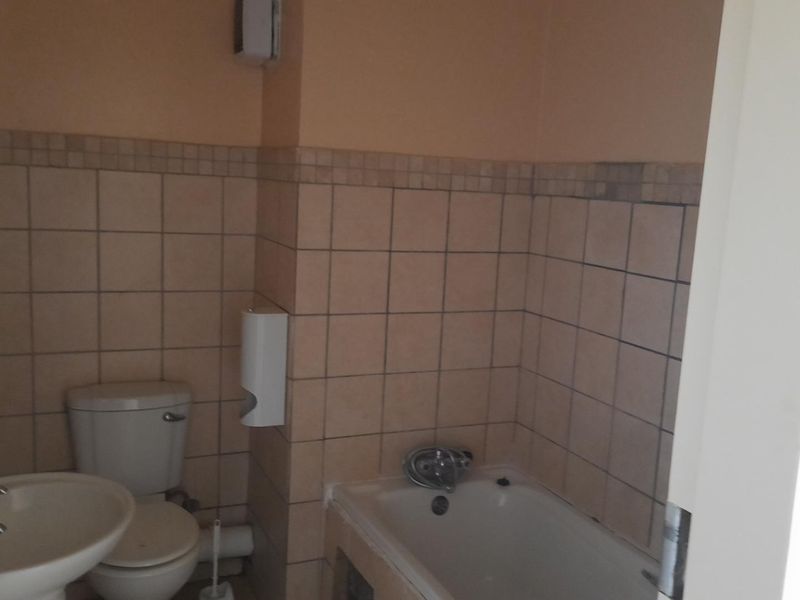 A functional bathroom featuring a pedestal basin, toilet, and bathtub with tiled walls, requiring cosmetic updates to modernize the space.