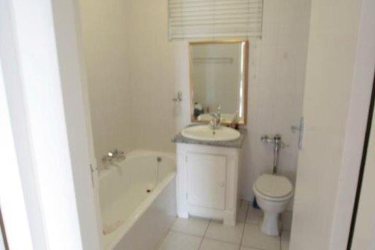 A functional bathroom featuring a white bathtub, a vanity with a basin, a toilet, and tiled flooring.