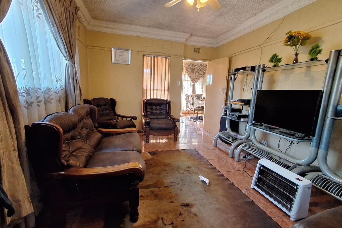 A living room featuring tiled flooring, a ceiling fan, and decorative cornicing, providing a functional space with potential for cosmetic updates.