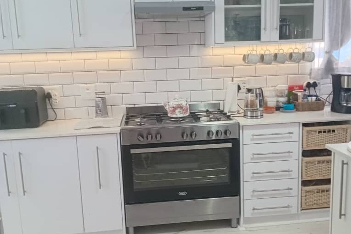 Modern kitchen featuring white cabinetry, subway tile backsplash, under-cabinet lighting, and a stainless steel gas stove with extractor fan.