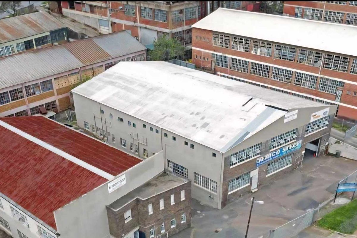 Aerial view of an industrial warehouse complex featuring multiple buildings with corrugated roofing and large multi-pane industrial windows.