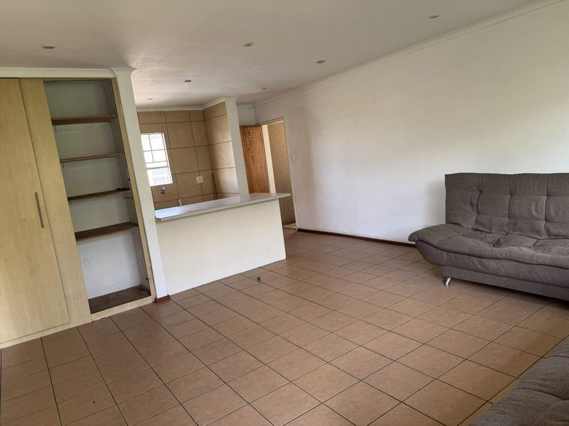 Open plan living area featuring tiled flooring, built-in cabinetry, and a breakfast bar connecting to the kitchen space.