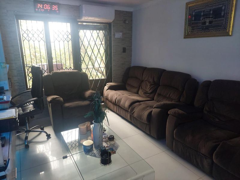 A comfortable living room featuring tiled flooring, a stone-cladding accent wall, and a split-system air conditioner, with direct access to an outdoor area.
