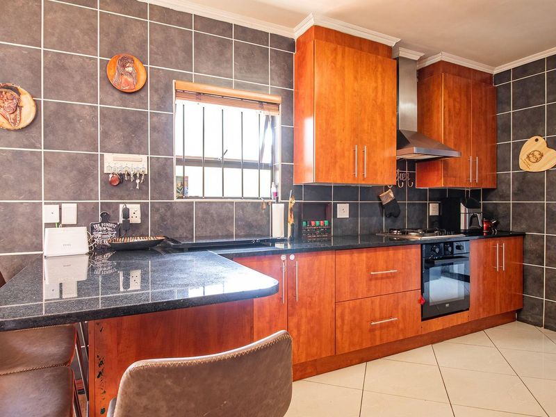 A functional kitchen featuring warm wood-toned cabinetry, dark granite countertops, a built-in oven with extractor fan, and a convenient breakfast nook.