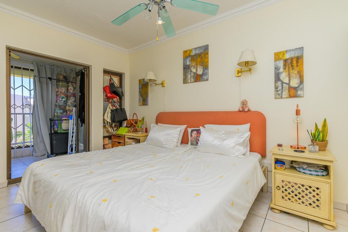 A bedroom featuring tiled flooring, a ceiling fan, wall-mounted lighting, and direct access to an outdoor balcony area.