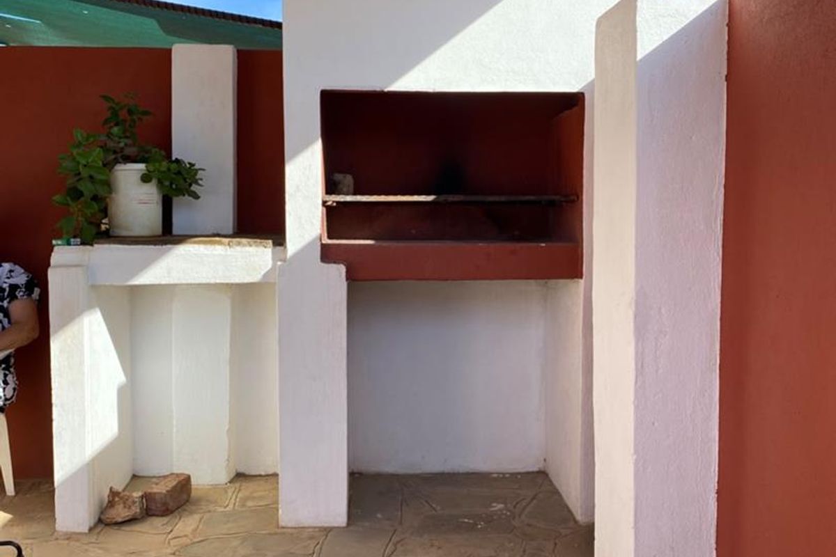 Outdoor patio area featuring a built-in braai, stone flooring, and a covered roof structure, ideal for entertaining.