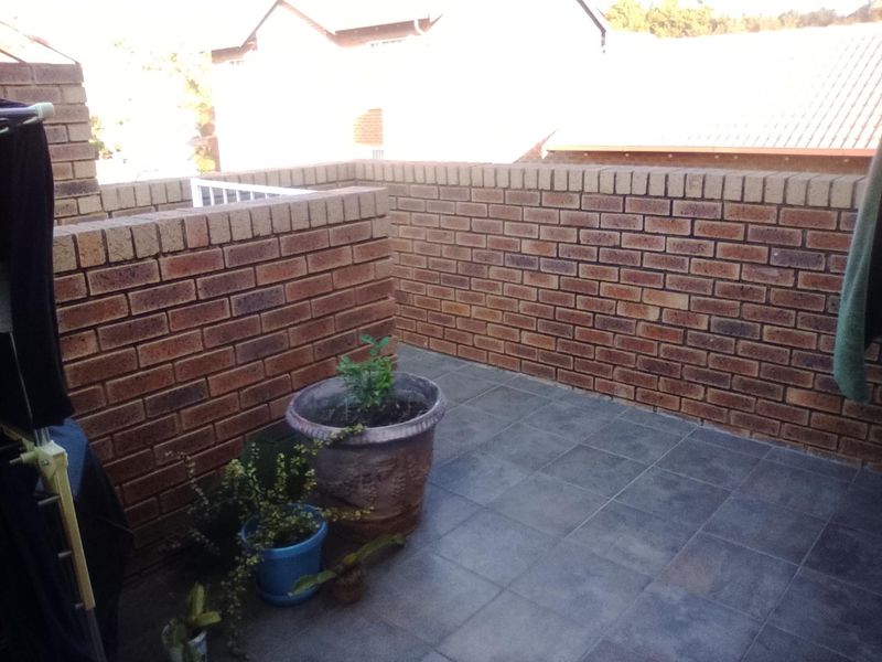 A private balcony area featuring durable brick parapet walls and tiled flooring, offering an open outdoor space.