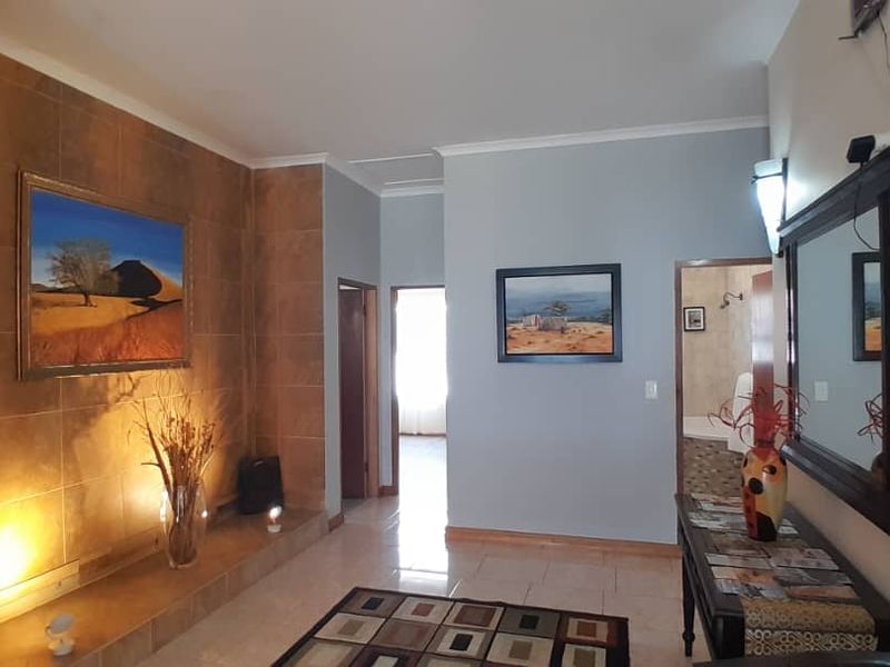 A well-maintained hallway featuring tiled flooring and a prominent tiled feature wall with integrated accent lighting.