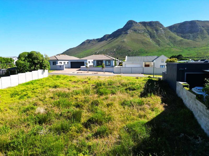 A vacant residential plot featuring boundary walls and scenic mountain views, situated in a developed neighborhood.