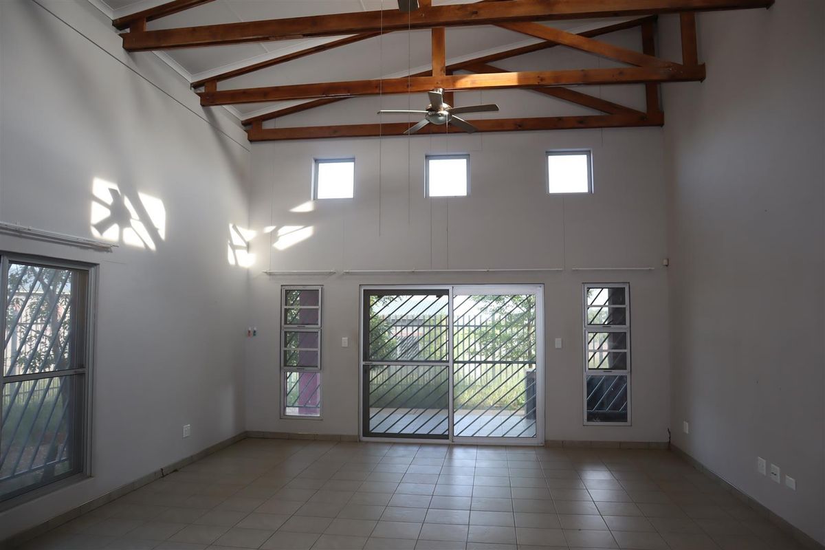 Spacious living area featuring high vaulted ceilings with exposed timber trusses, tiled flooring, and large sliding doors providing access to the exterior.