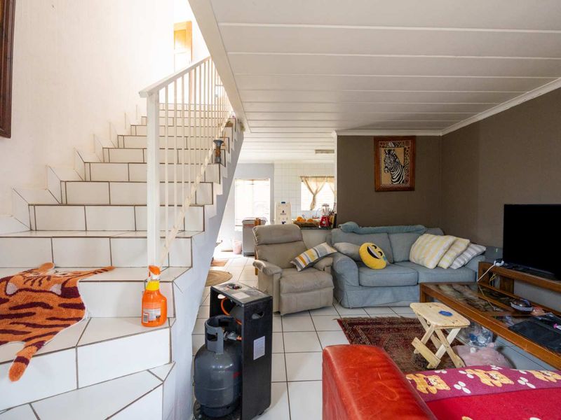 Open plan living area featuring a tiled staircase with metal balustrade, leading towards a kitchen space with neutral wall finishes.