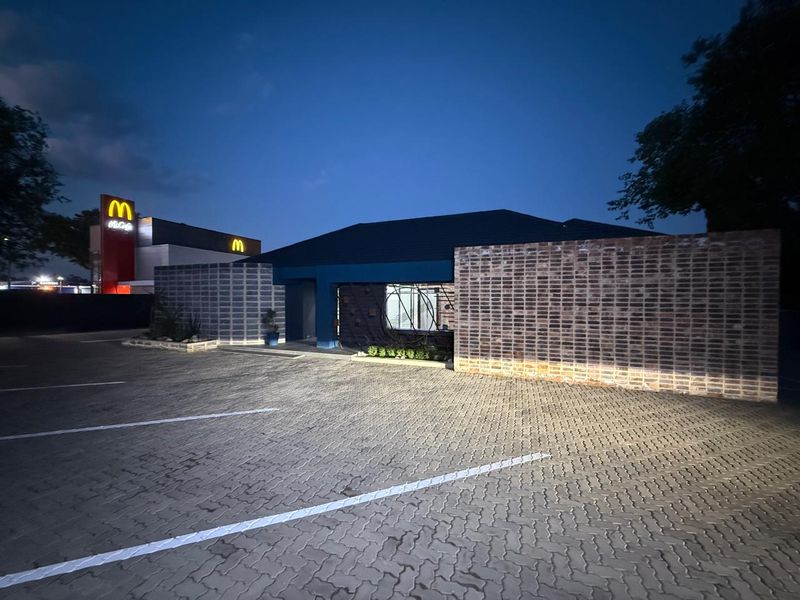Front exterior view of the commercial property featuring a paved parking area and modern brick facade at dusk.
