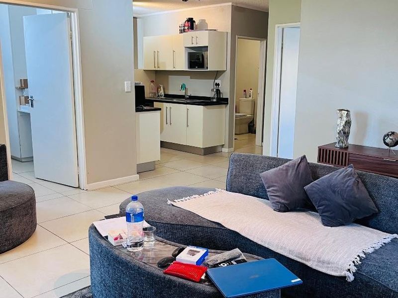 Open plan living area featuring tiled flooring and a functional kitchen with built-in cabinetry and integrated microwave.