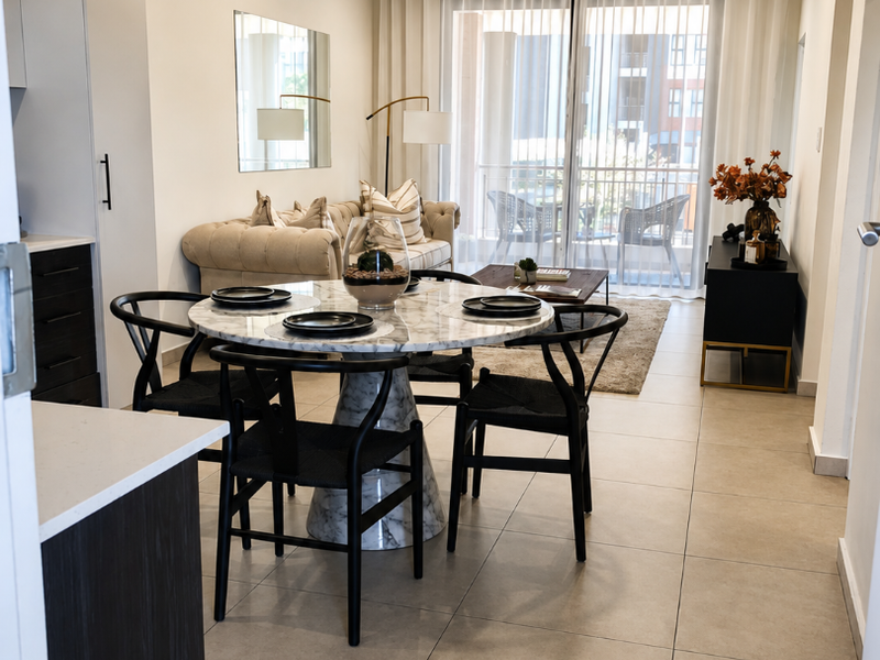Modern open-plan living and dining area featuring neutral tiled flooring, recessed lighting, and seamless access to a private balcony through large sliding glass doors.