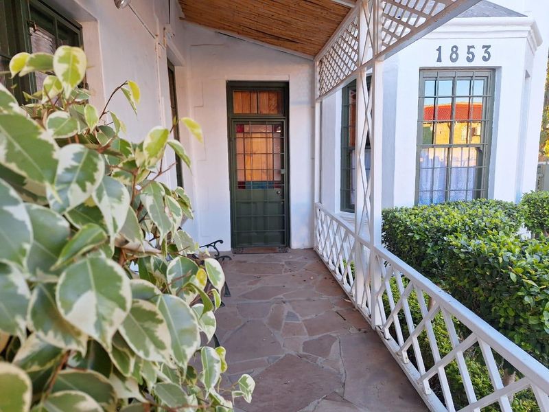 A covered patio entrance featuring stone paving, a lattice railing, and security fixtures, providing a charming and secure access point to the property.