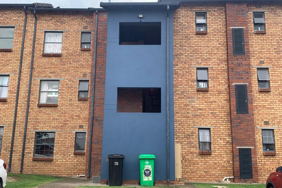 Rear elevation of a multi-story brick apartment building featuring exposed structural openings where windows are missing.