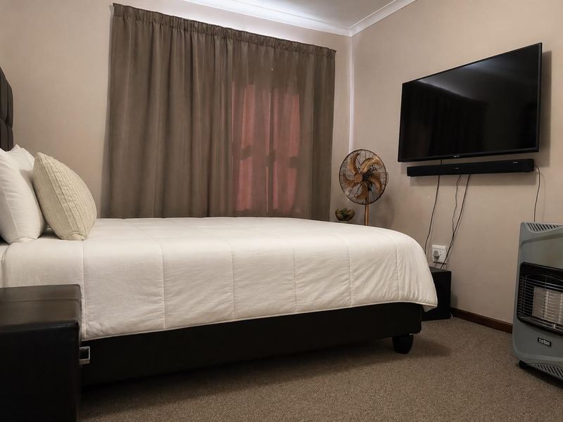A functional bedroom featuring neutral wall tones, carpeted flooring, and decorative cove cornicing, providing a comfortable and well-maintained living space.