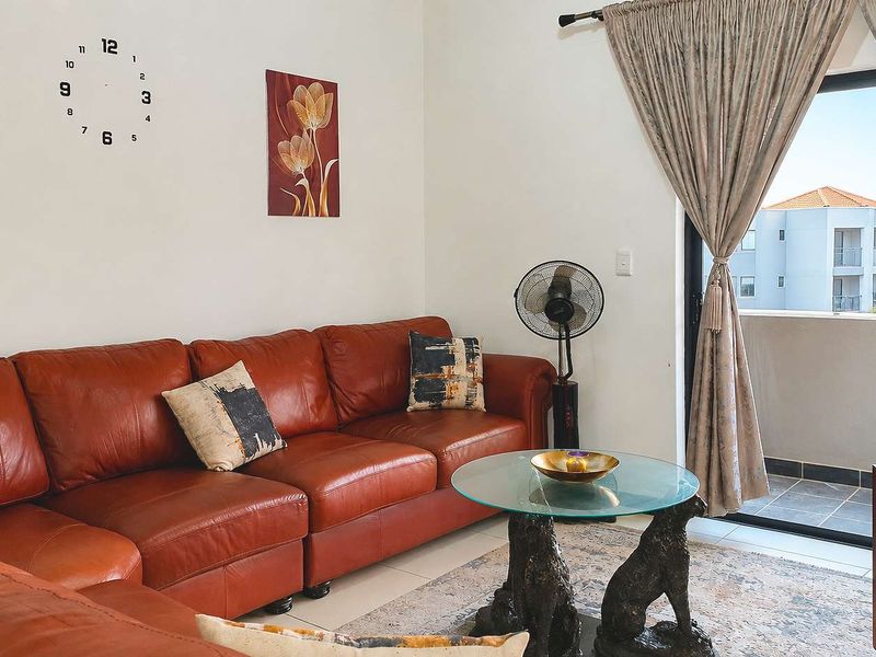 A living room featuring tiled flooring and a sliding glass door providing access to an outdoor balcony area.