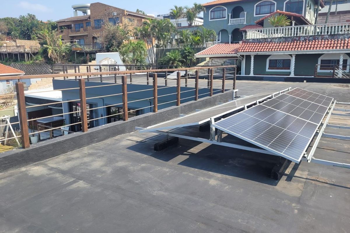 A flat roof terrace featuring a solar panel installation, timber railing, and views of the surrounding residential neighborhood.