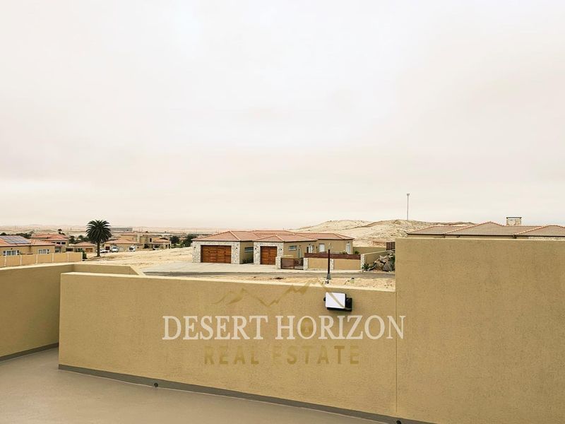 Elevated view overlooking a residential estate with desert landscape and surrounding properties.