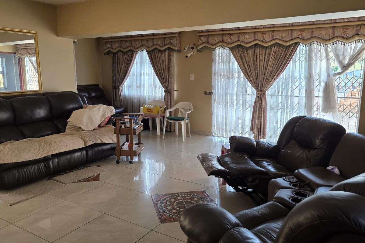 Spacious living room featuring large format floor tiles, sliding glass doors with security gates, and a large wall-mounted mirror.