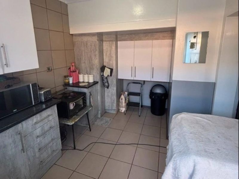 A compact kitchen area featuring tiled flooring, built-in cabinetry, and a tiled backsplash, offering a functional layout with potential for modernization.