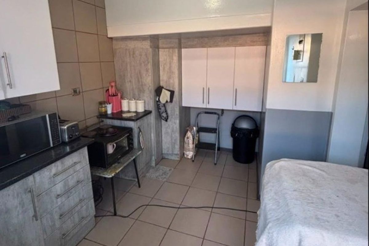 A compact kitchen area featuring tiled flooring, built-in cabinetry, and a tiled backsplash, offering a functional layout with potential for modernization.