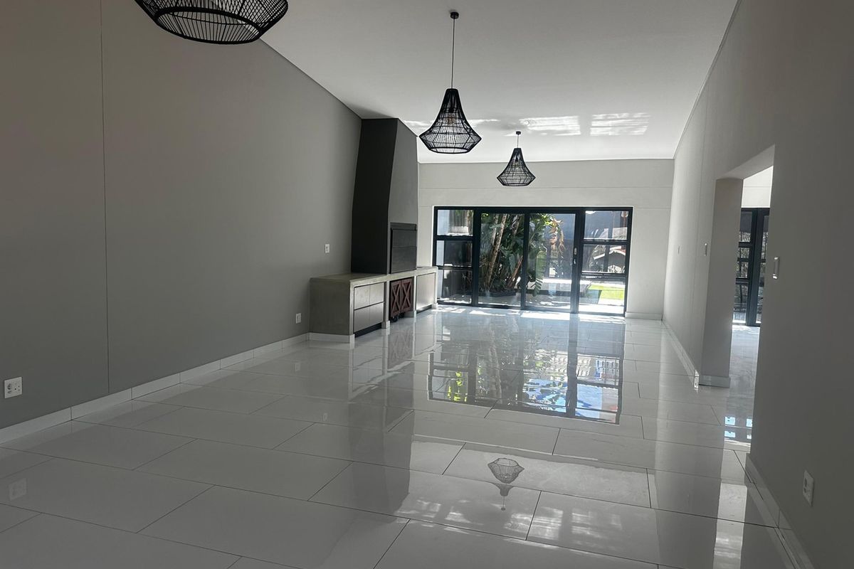 Spacious, modern living area featuring polished tile flooring, a built-in fireplace, and large sliding glass doors that open to the garden.