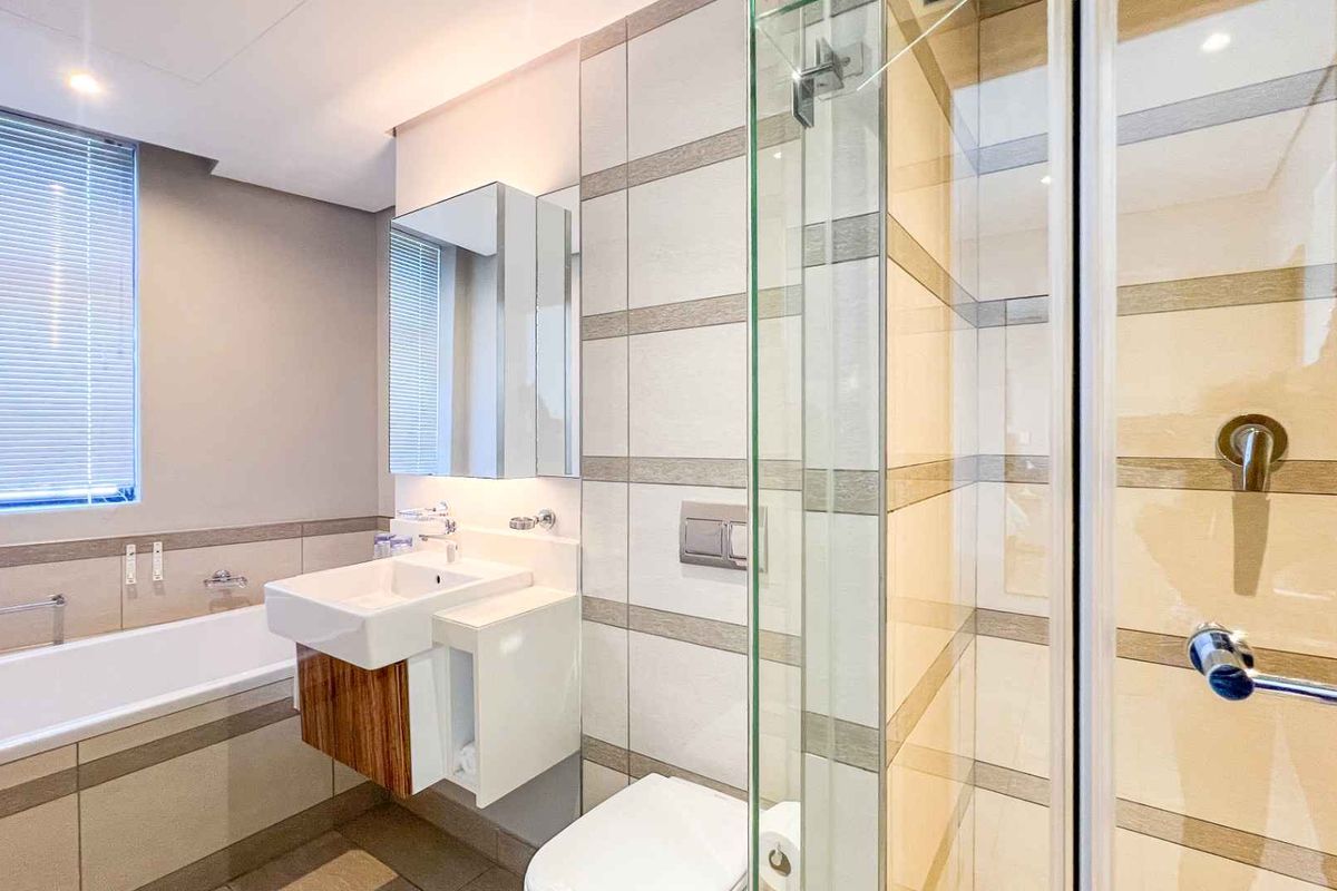 Modern bathroom featuring a wall-mounted vanity, a deep soaking bathtub, and a glass-enclosed walk-in shower with contemporary tiled finishes.