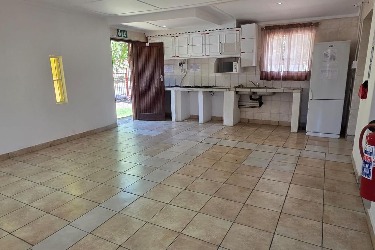 A functional open-plan kitchen area featuring tiled flooring, built-in cabinetry, and direct access to the exterior.